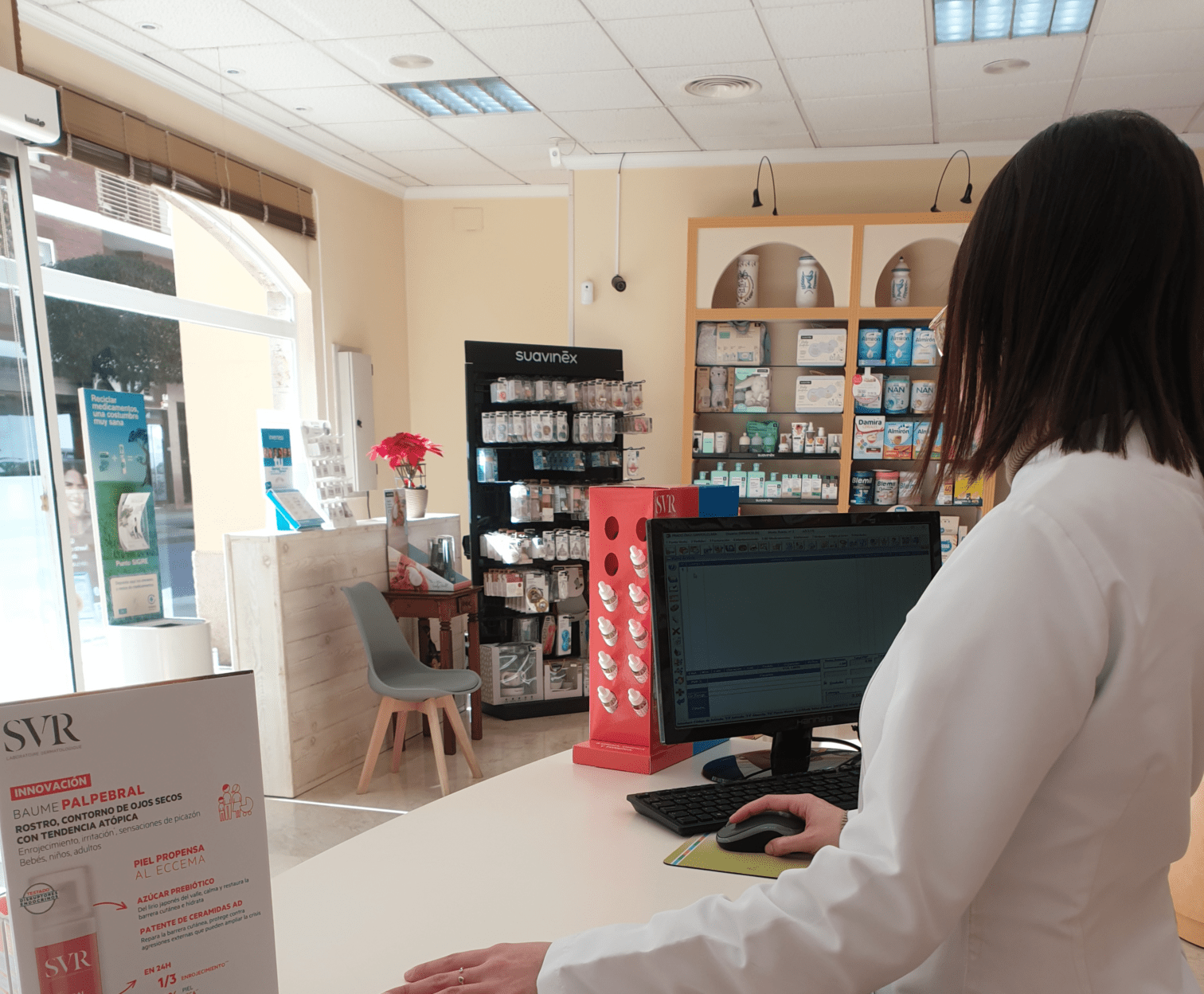 Farmacéutica en mostrador con ordenador, servicio Click and Collect farmacia clara prado